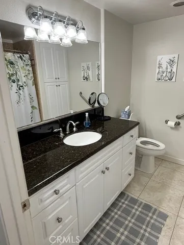 a bathroom with a granite countertop sink a toilet and a mirror