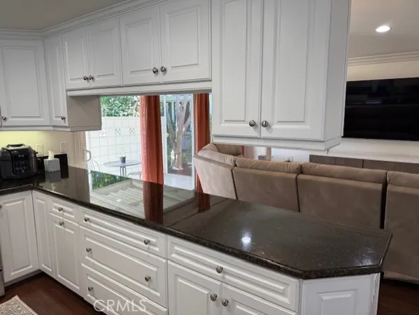 a kitchen with granite countertop a stove and white cabinets
