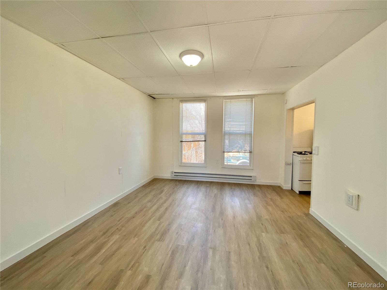 2422 West Vermijo Avenue, Unit 7 Colorado Springs, CO 80904 - Photo 3 of 6 an empty room with wooden floor and windows