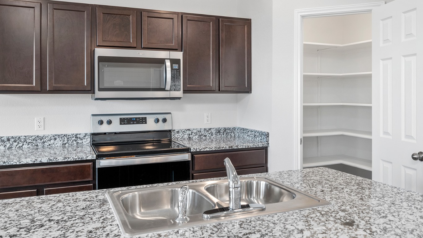 1416 Coriander Road Temple, TX 76501 - Photo 5 of 22 Kitchen featuring dark brown cabinets, stainless steel appliances, and light stone counters