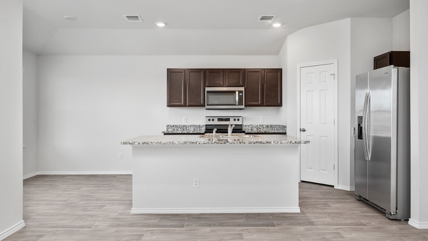1416 Coriander Road Temple, TX 76501 - Photo 8 of 22 Kitchen featuring appliances with stainless steel finishes, dark brown cabinets, light stone counters, light wood-style floors, and recessed lighting