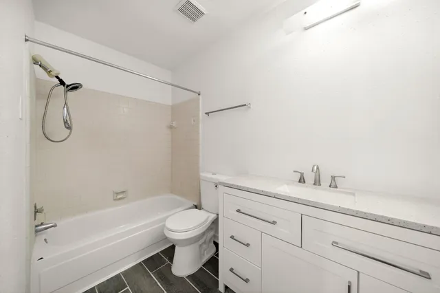 a bathroom with a granite countertop sink a toilet and a bathtub