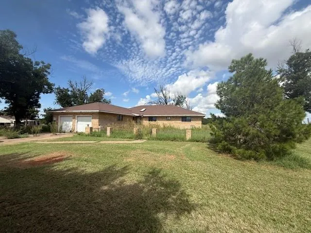a view of a big house with a big yard and large trees