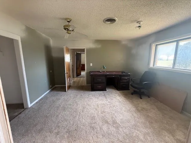 an empty room with windows and fan