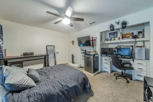 a bedroom with a bed a desk and book shelfs