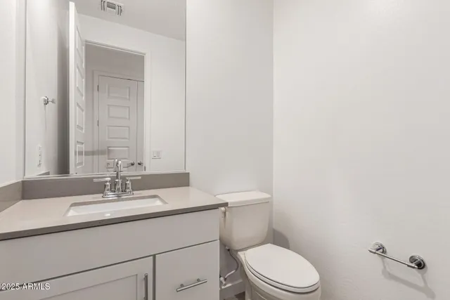 a bathroom with a granite countertop toilet sink mirror and vanity