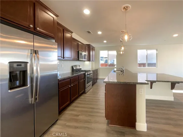 a kitchen with stainless steel appliances granite countertop a refrigerator a sink and a stove