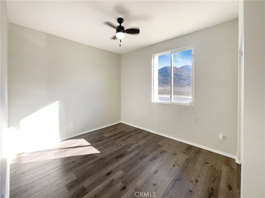 26625 Emperor Road Menifee, CA 92585 - Photo 8 of 24 an empty room with wooden floor and windows
