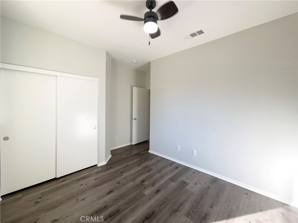 26625 Emperor Road Menifee, CA 92585 - Photo 9 of 24 an empty room with wooden floor ceiling fan and window