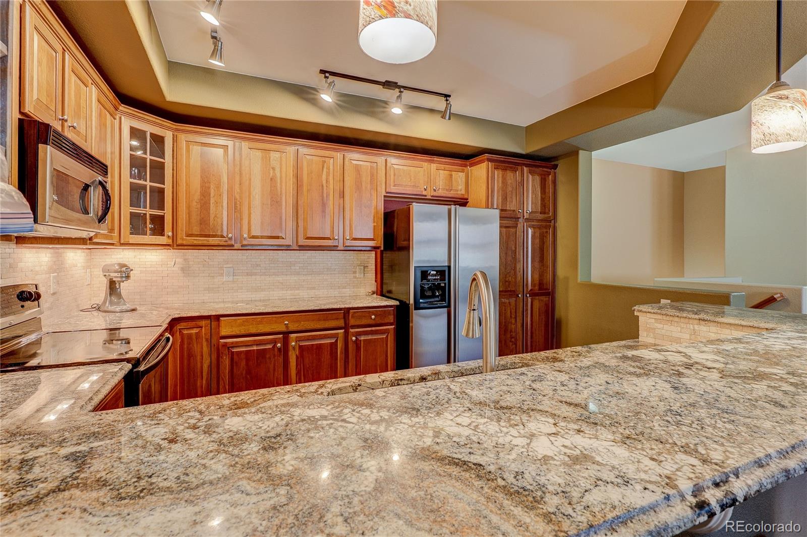 10556 Graymont Lane, Unit B Highlands Ranch, CO 80126 - Photo 14 of 40 a kitchen with stainless steel appliances kitchen island granite countertop a refrigerator sink and cabinets