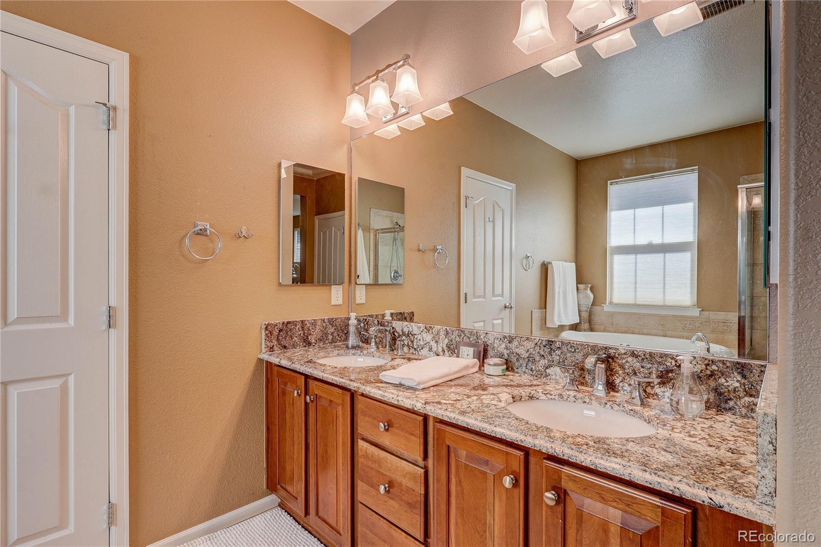 10556 Graymont Lane, Unit B Highlands Ranch, CO 80126 - Photo 19 of 40 a bathroom with a granite countertop double vanity sink a vanity and a large mirror