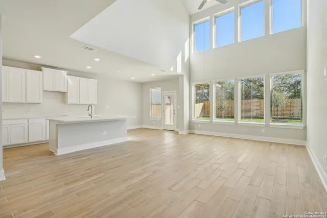 a view of an empty room with wooden floor and kitchen