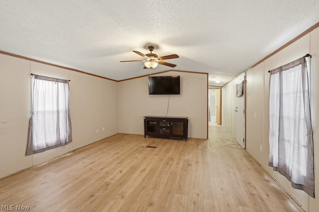 6507 Robby Lane Ravenna, OH 44266 - Photo 6 of 25 Unfurnished living room with light wood finished floors, ceiling fan, and crown molding