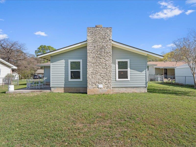 1312 Hyman Lane Austin, TX 78742 - Photo 35 of 36 The property features a stone chimney, siding exterior, and a well-maintained lawn