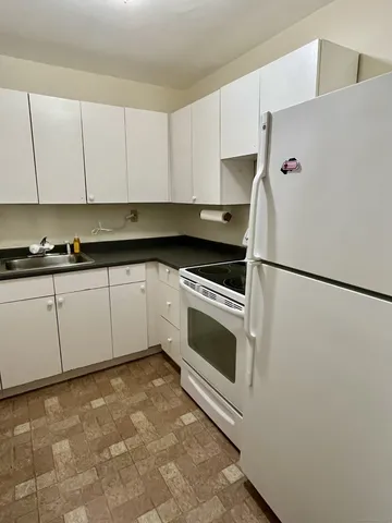 a kitchen with granite countertop white cabinets and white appliances