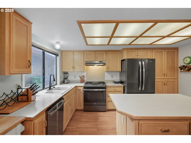 a kitchen with kitchen island a counter top space a sink stainless steel appliances and cabinets