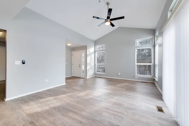 a view of an empty room with a window and a kitchen