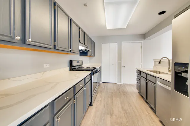 a kitchen with granite countertop cabinets stainless steel appliances and wooden floor