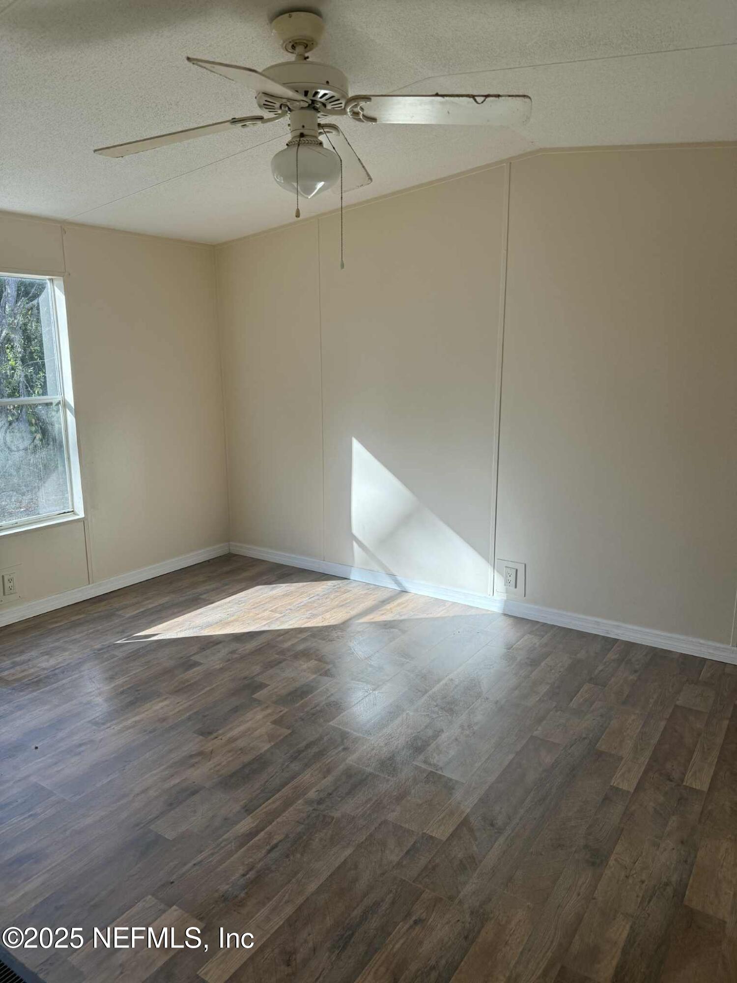 550 Interlachen Boulevard Interlachen, FL 32148 - Photo 11 of 15 an empty room with wooden floor fan and windows