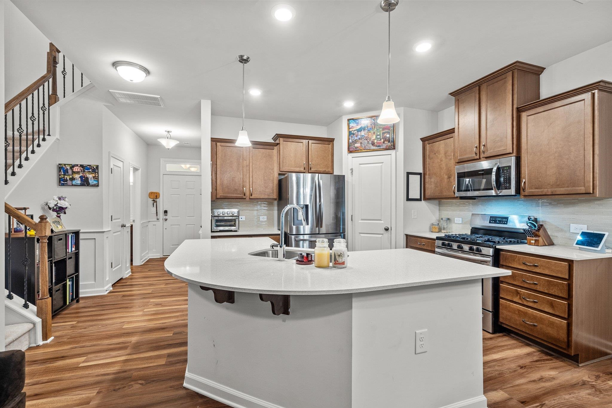 6085 Beale Loop Raleigh, NC 27616 - Photo 5 of 42 a kitchen with stainless steel appliances kitchen island granite countertop a stove a sink a refrigerator and white cabinets with wooden floor