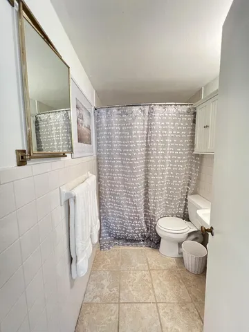 a bathroom with a toilet a sink a shower and mirror