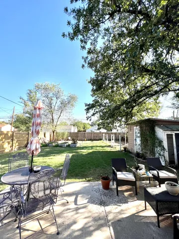 a view of a patio with dining table and chairs with a yard