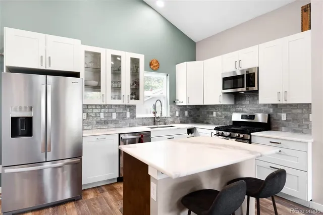a kitchen with a refrigerator a stove a sink and white cabinets