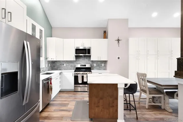 a large kitchen with stainless steel appliances a refrigerator a stove a sink a dining table and chairs