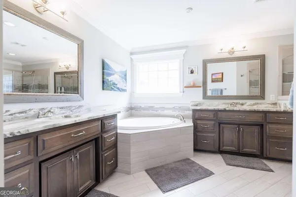 a bathroom with a granite countertop bathtub a sink and a large mirror