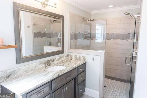 a bathroom with a granite countertop sink a mirror and a shower