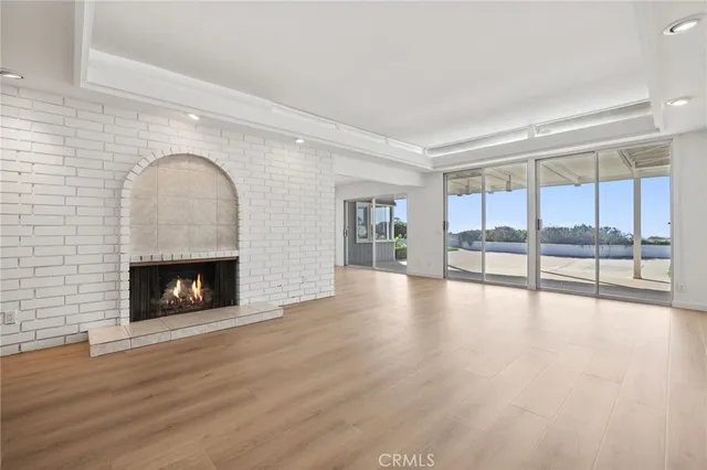 a view of an empty room with wooden floor and a fireplace