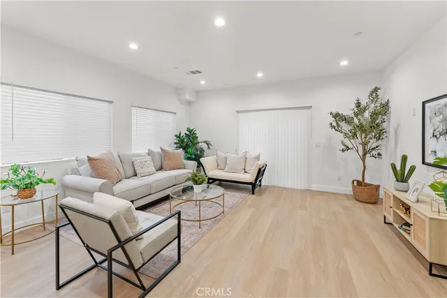 a living room with furniture white walls and a dining table with kitchen view