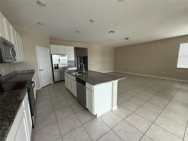 a kitchen with granite countertop a sink a stove top oven and cabinetry