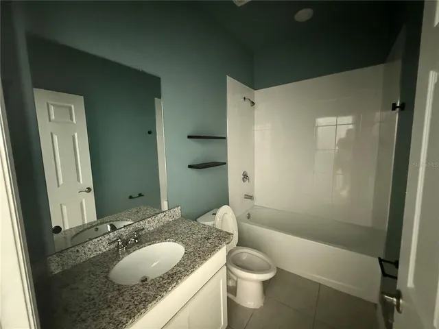 a bathroom with a granite countertop sink toilet mirror and shower