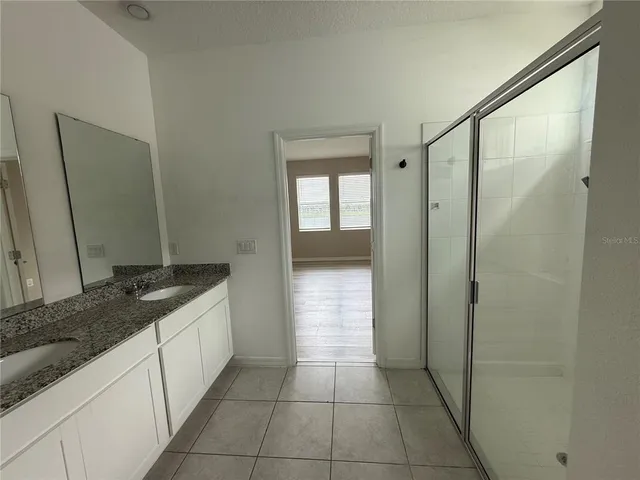 a bathroom with a granite countertop sink a mirror and a shower