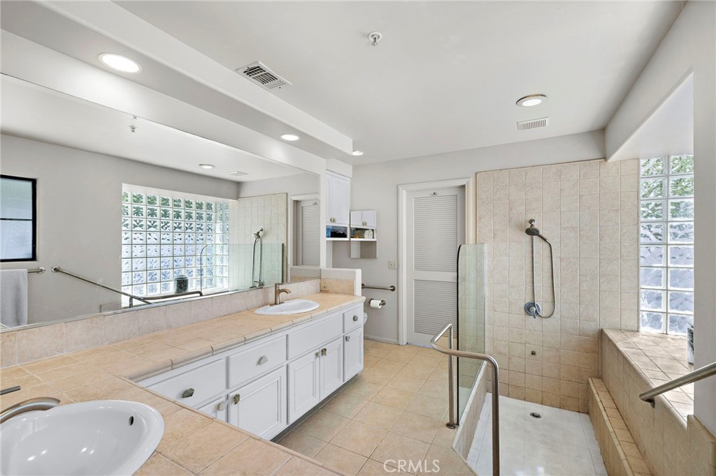 31645 Rancho Viejo Road San Juan Capistrano, CA 92675 - Photo 9 of 10 a spacious bathroom with a double vanity sink a large mirror a bathtub and next to a window