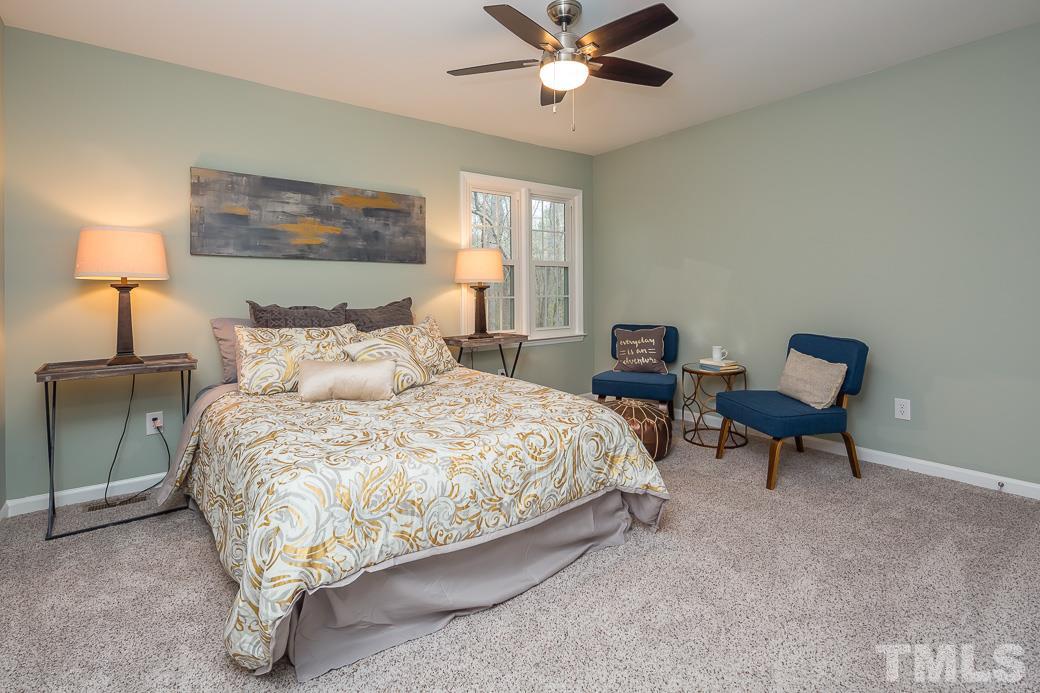 6241 Waterside Lane Raleigh, NC 27613 - Photo 9 of 16 a spacious bedroom with a bed a chair and potted plant on the dresser