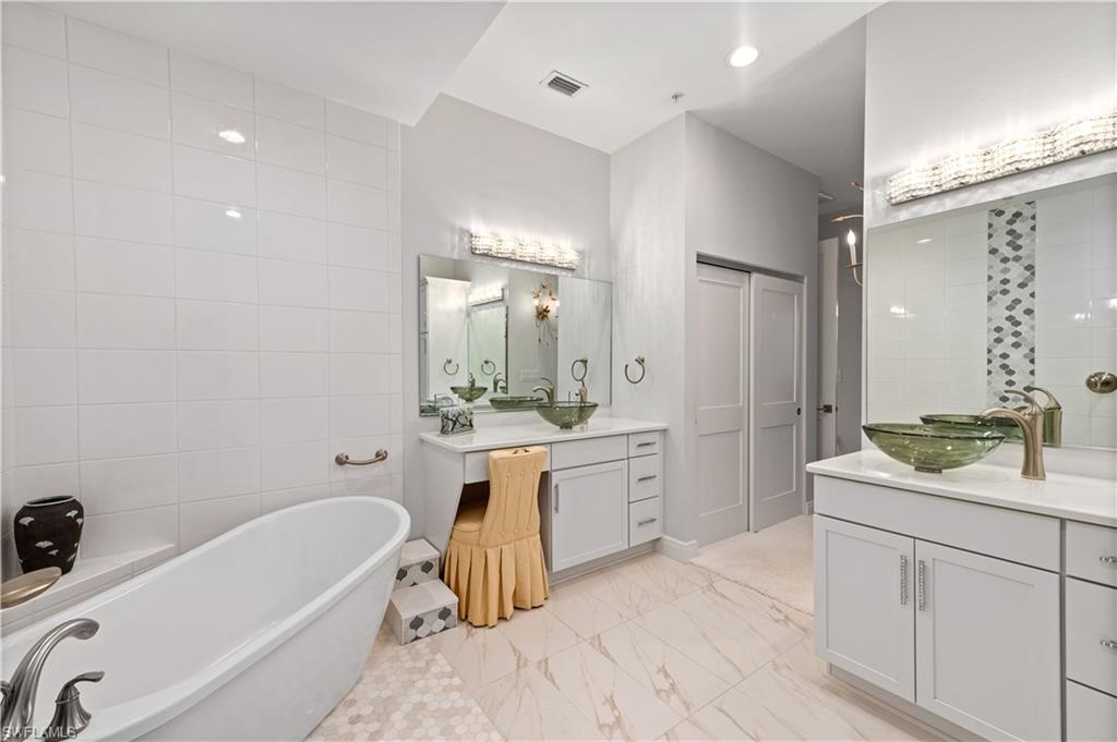 21490 Strada Nuova Circle, Unit D211 Estero, FL 33928 - Photo 24 of 45 a bathroom with a tub a sink double vanity and a mirror