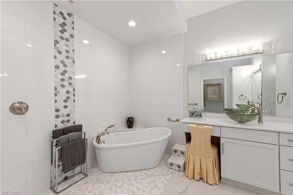21490 Strada Nuova Circle, Unit D211 Estero, FL 33928 - Photo 26 of 45 a bathroom with a bathtub a sink and a mirror