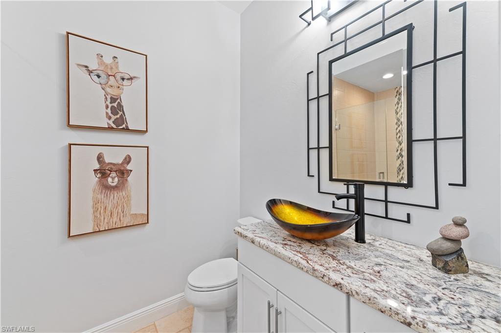 21490 Strada Nuova Circle, Unit D211 Estero, FL 33928 - Photo 28 of 45 a bathroom with a granite countertop toilet sink and mirror
