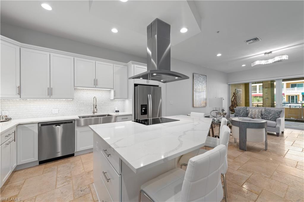 21490 Strada Nuova Circle, Unit D211 Estero, FL 33928 - Photo 6 of 45 a large kitchen with kitchen island a sink a stove a dining table and chairs