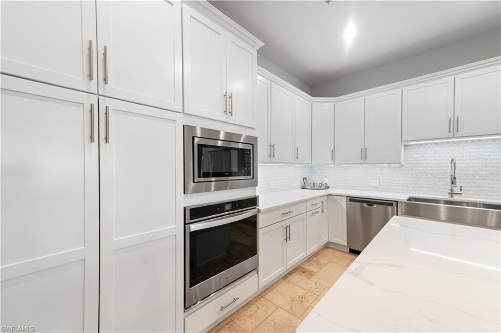 21490 Strada Nuova Circle, Unit D211 Estero, FL 33928 - Photo 7 of 45 a kitchen with white cabinets and white appliances