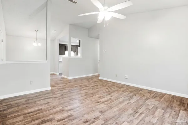 an empty room with wooden floor and fan