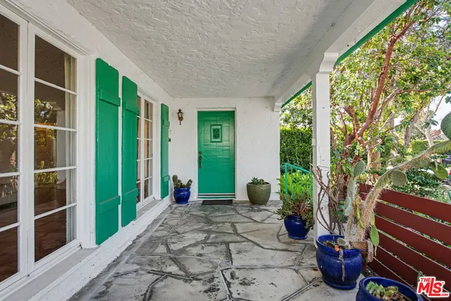 a view of a porch with potted plants and floor to ceiling window