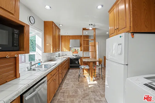 a kitchen with granite countertop a sink appliances and cabinets