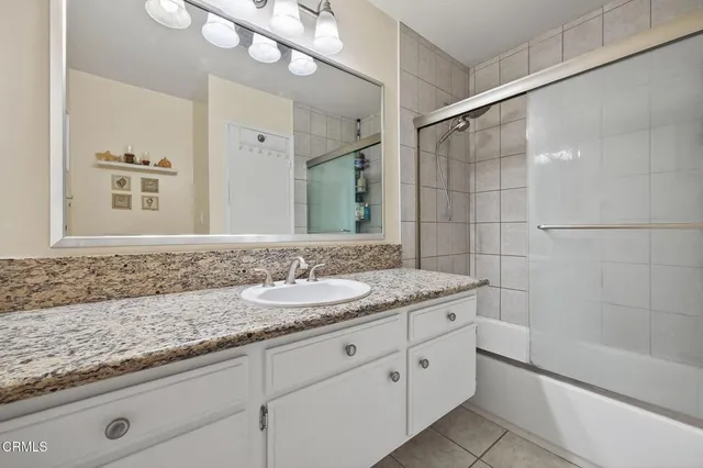 a bathroom with a granite countertop sink a mirror and a shower