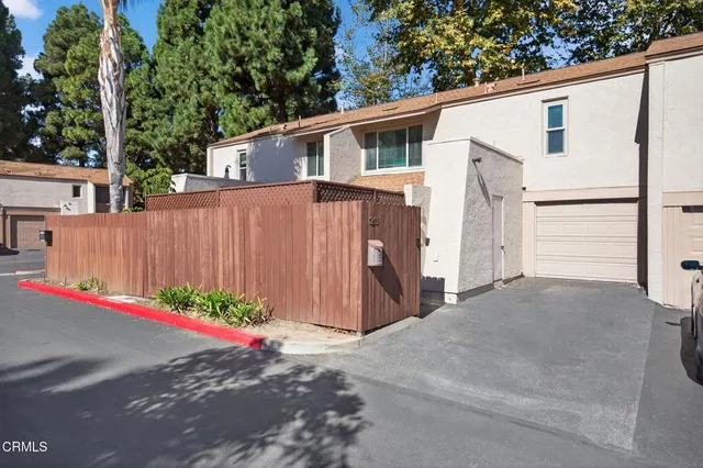 a view of a white house with a small yard and a large parking space