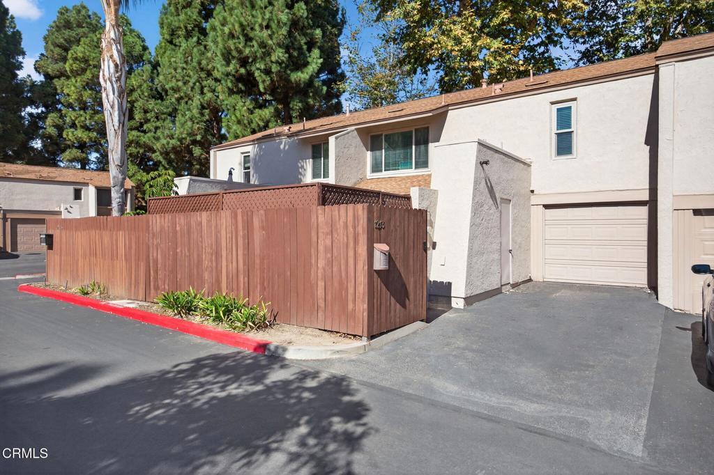 1213 Nilgai Place Ventura, CA 93003 - Photo 19 of 22 a view of a white house with a small yard and a large parking space