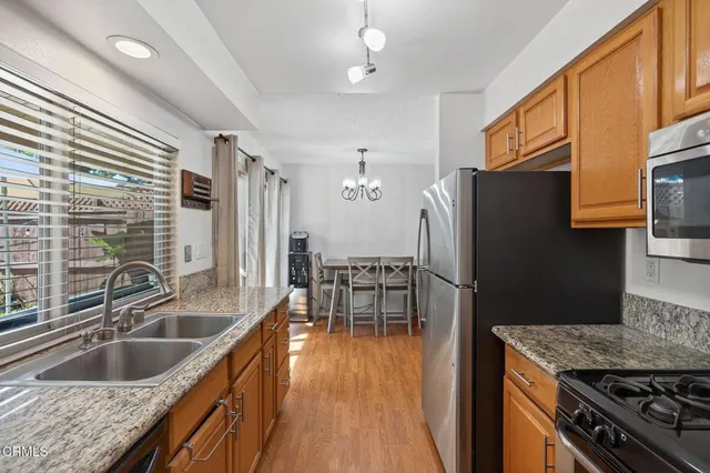 a kitchen with granite countertop a sink a counter space stainless steel appliances and dining table