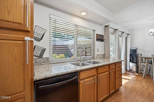 a kitchen with stainless steel appliances granite countertop a sink and a wooden floor